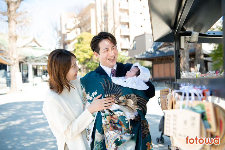 お宮参りで赤ちゃんを抱えて微笑む夫婦の写真