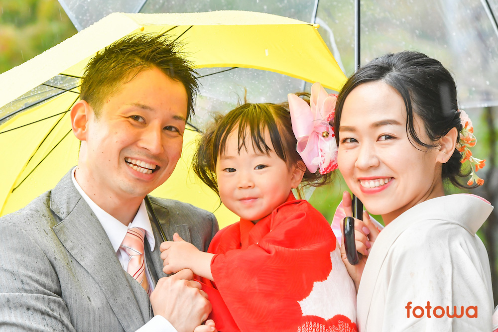 傘を差しながら微笑む家族