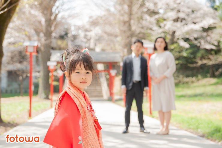 桜の前に立つ夫婦と和装の子ども
