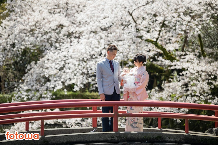 桜の前で子どもを見つめる夫婦