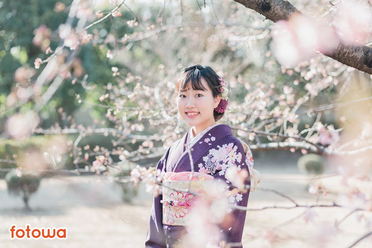 桜の木の下で微笑む振袖姿の女性