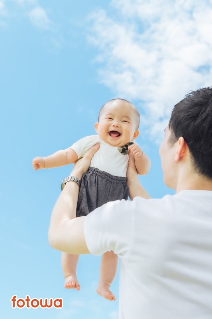 ハーフバースデーの撮影で青空の下で笑顔いっぱいの赤ちゃん