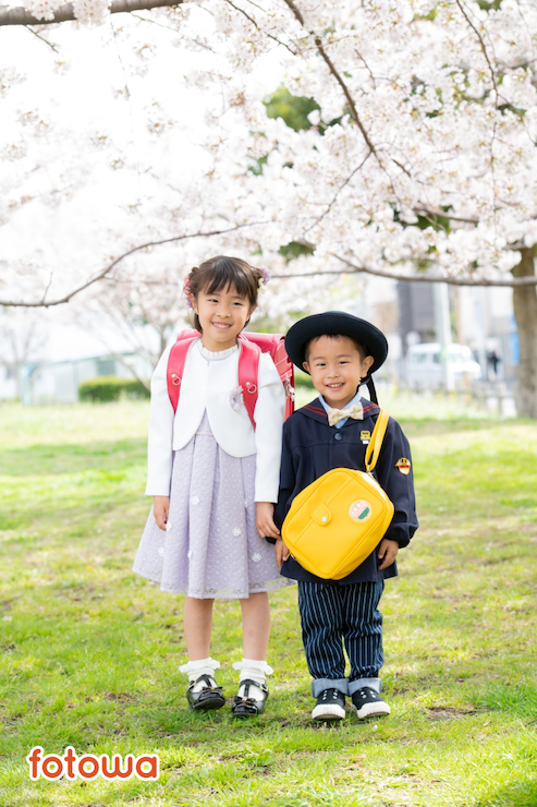桜の下で撮影された入学祝いの写真