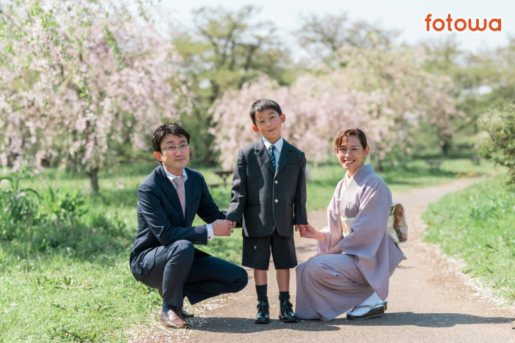 桜を背景に撮影した入学祝いの親子写真