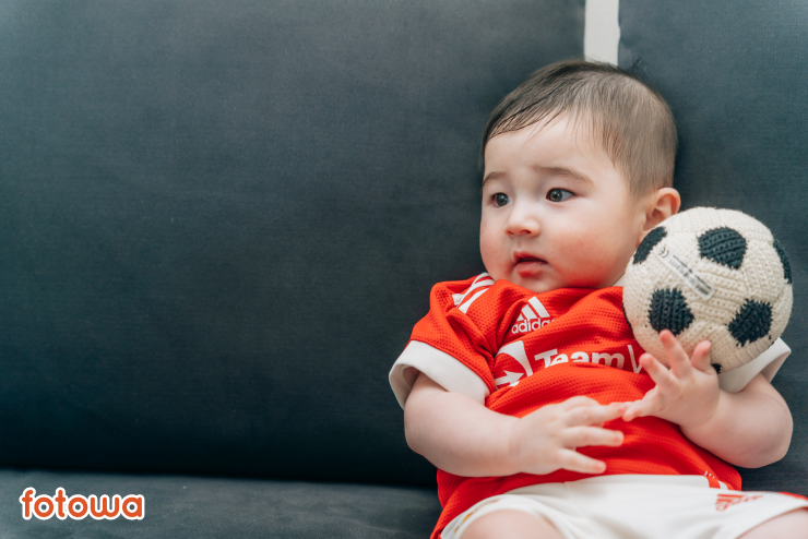 サッカーのユニフォームを着た赤ちゃんのハーフバースデー写真事例