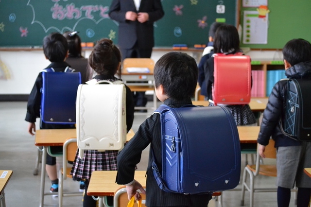 入学式当日の教室で子ども達が机の前に立っている様子