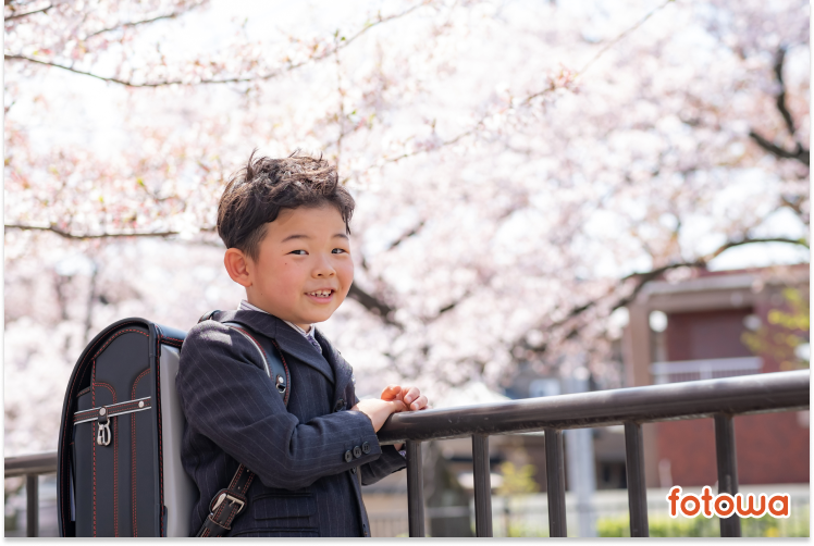 桜の木の前でランドセルを背負って立っている男の子の入学写真事例