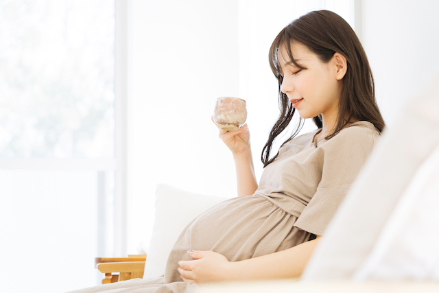 温かい飲み物を飲んで休憩している妊娠中の女性