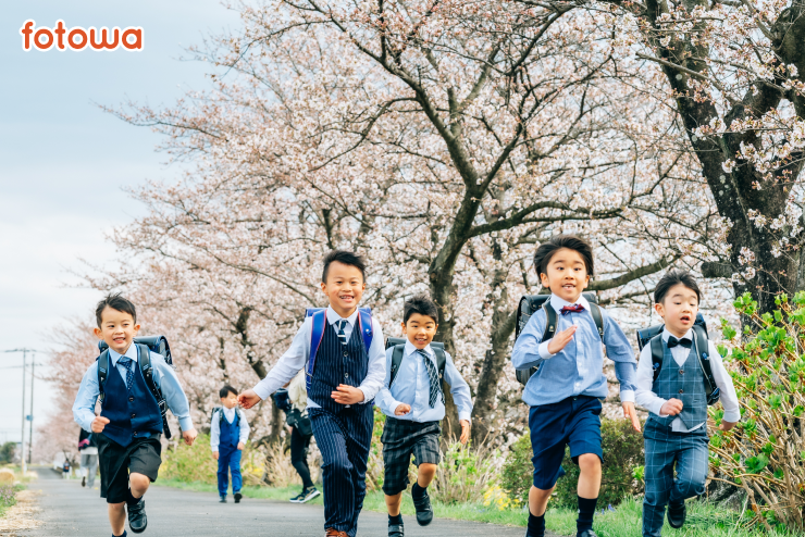 桜並木を走り抜ける卒園・入学を迎えるランドセルを背負った子どもたち